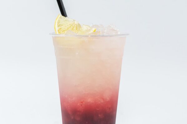 Rev Burger Berry Burst layered lemonade with strawberry and blueberry, garnished with a lemon slice and black straw